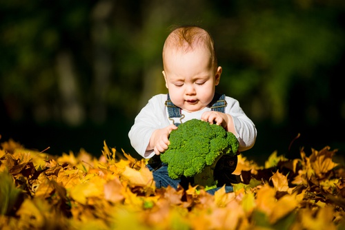 neonato con broccoli tra le mani