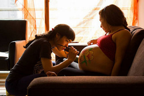 ragazza-disegna-pancia-di-donna-incinta