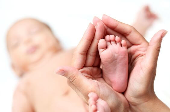 L'arrivo di un figlio cambia la vita: una mamma tiene tra le mani il piedino del suo neonato.