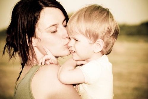 Una giovane mamma bacia il suo bimbo.