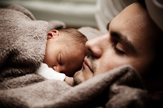 Un papà dorme con un neonato: diventare padre cambia la vita.