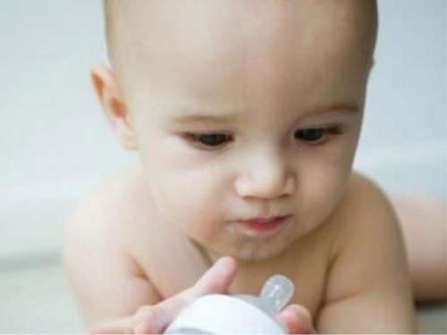 Un bambino che gioca con il suo biberon e non beve latte.