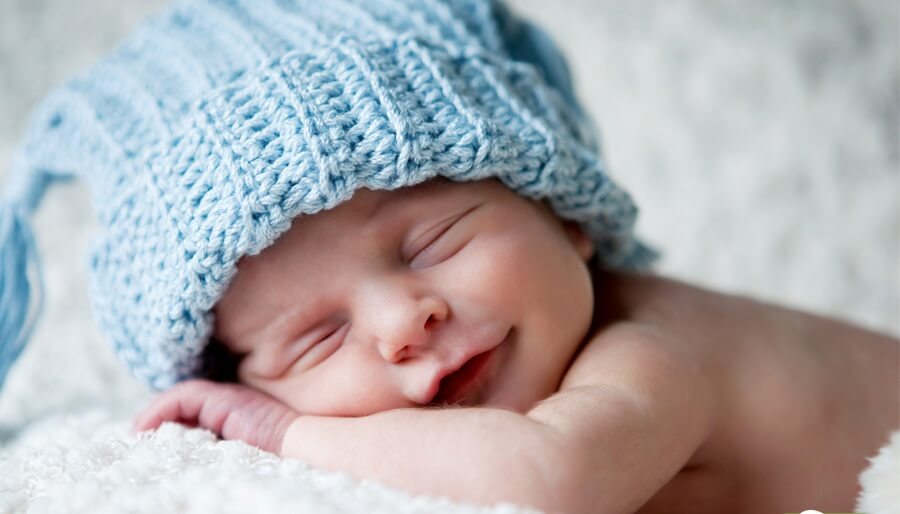 Un neonato dorme con una cuffietta.