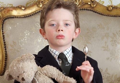 Un bambino narcisista, seduto su una poltrona principesca.