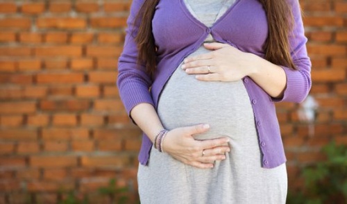 Donna incinta che si tocca la pancia; qual'è l'età giusta per diventare madre?
