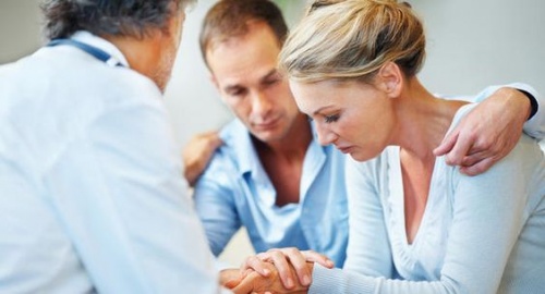 Un medico spiega a una coppia le cause dell'aborto spontaneo.