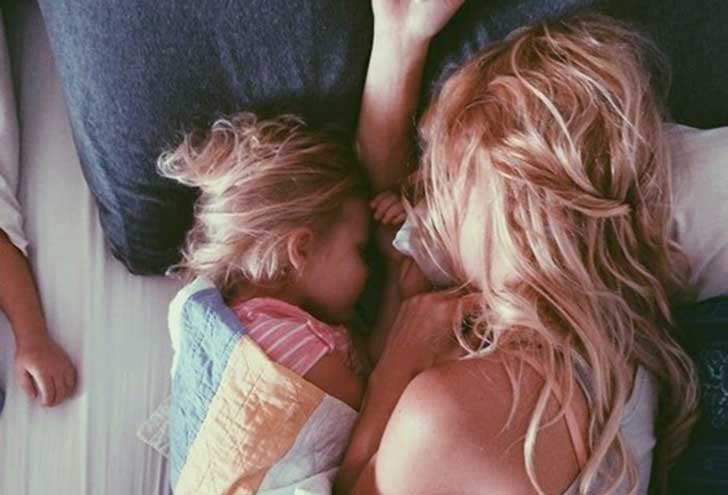 Mamma dorme con la figlia sul letto.