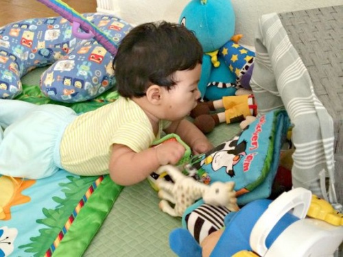 Neonato a carponi che gioca e impara a gattonare