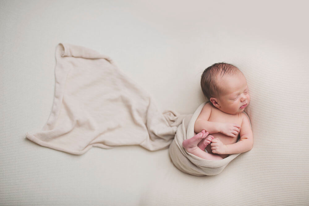 Neonato avvolto in un lenzuolo.