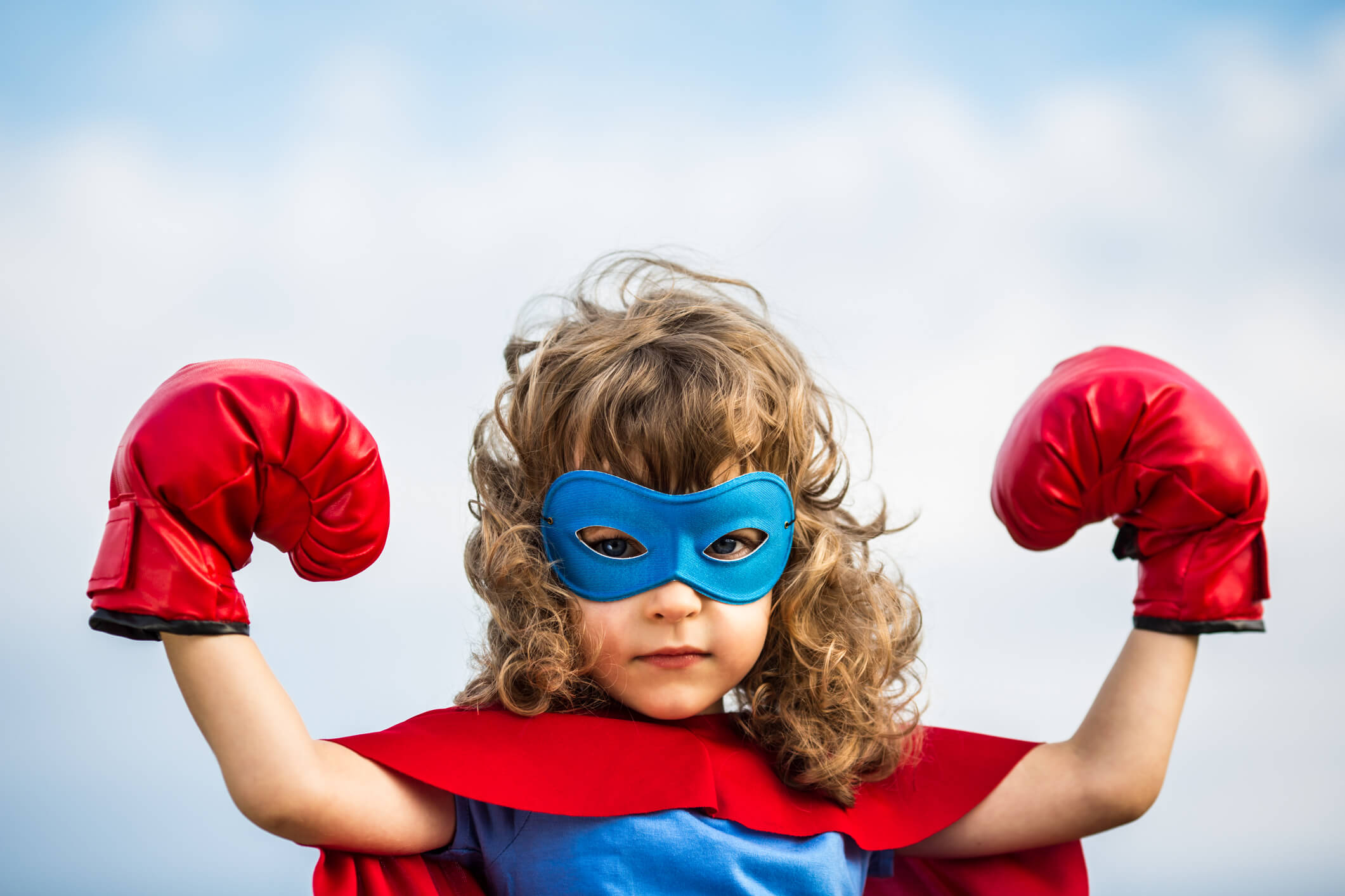Bambina mascherata da Superman, con maschera e guantoni.
