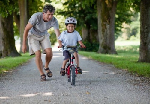 Crescere bambini felici: un padre insegna al figlio ad andare in bicicletta.