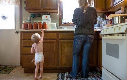 A casa un bimbo guarda i barattoli di conserva preparati dalla mamma.