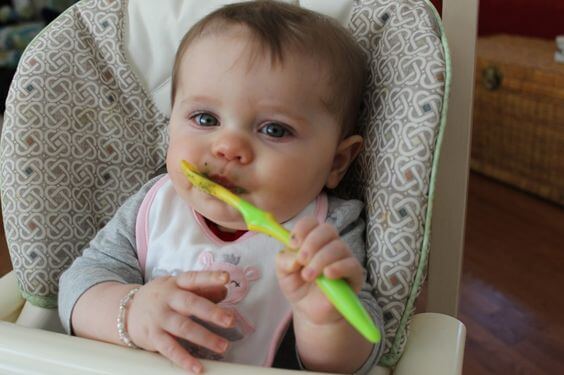 neonato mangia da solo con cucchiaio