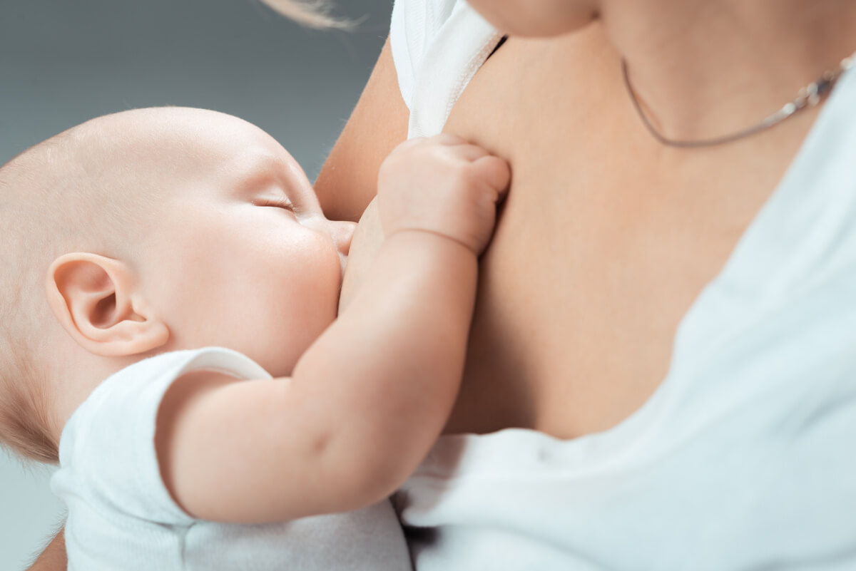 Neonato in braccio alla mamma mentre prende il latte