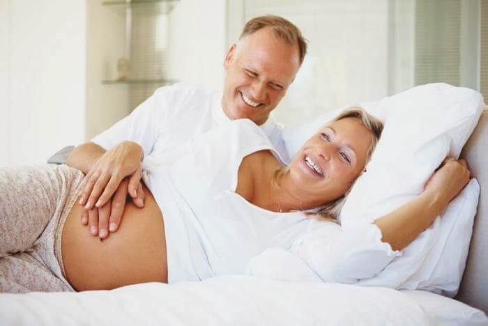 Donna incinta sorride insieme al marito