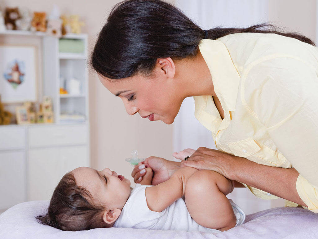Mamma che parla al suo bambino mentre lo cambia