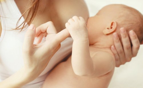 Neonato che afferra il dito della mamma