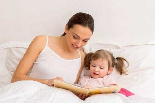 Mamma legge libro a letto con la figlia