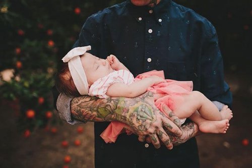 Padre tatuato tiene in braccio la figlia
