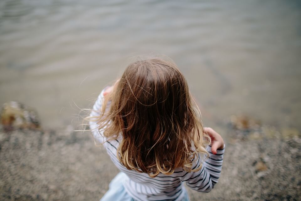 Bambina di spalle davanti all'acqua