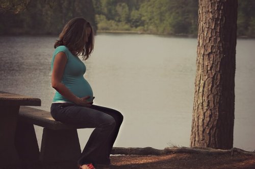 Donna incinta seduta vicino a un lago