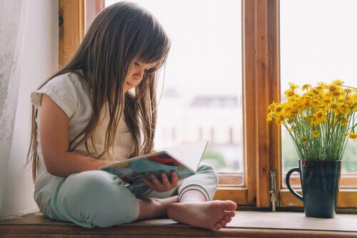 Bambina legge seduta alla finestra