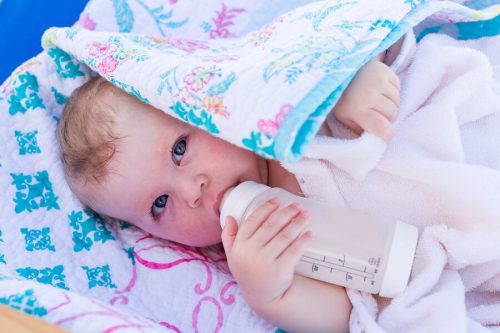 Bambino prende il biberon protetto dal sole