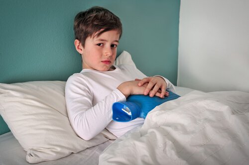 Bambino a letto con una borsa dell'acqua calda sulla pancia