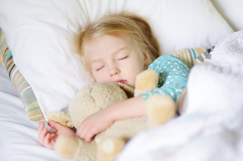 Bambina che dorme con peluche