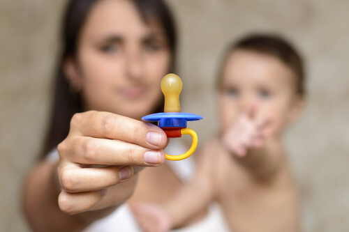 mamma con ciuccio in mano e bambino in braccio