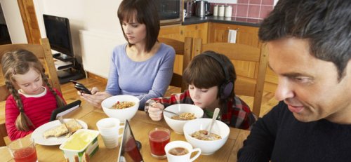 famiglia che usa la tecnologia a tavola