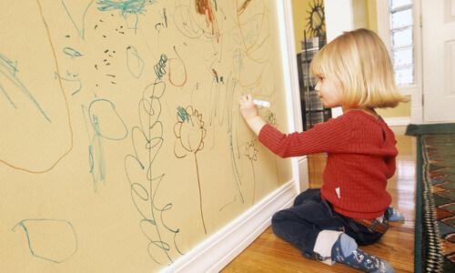 bambina che disegna sul muro con pennarello 