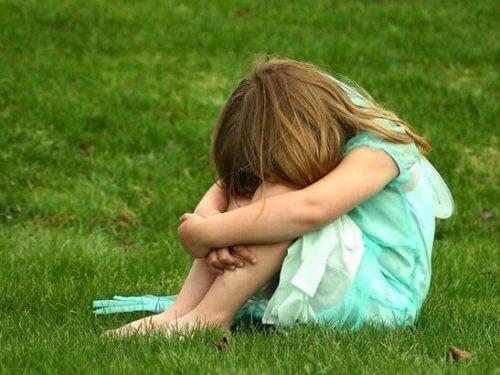 bambina con la testa bassa in mezzo al prato 