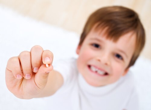 Bambino con dente da latte in mano