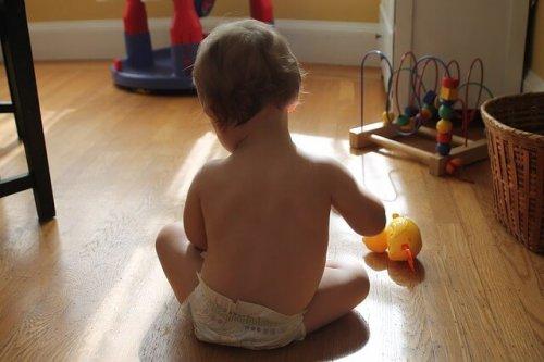 bambino con pannolino che gioca sul pavimento