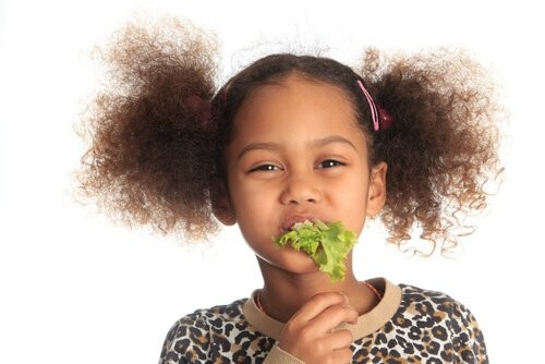 Bambina che mangia insalata