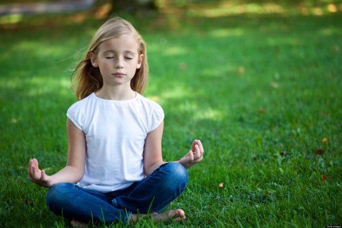 Bambina fa meditazione su un prato