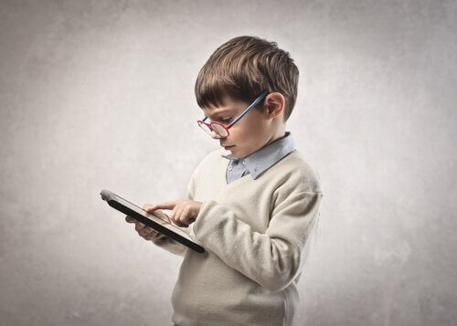 bambino con occhiali in piedi usa tablet