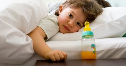bimba a letto di lato con tazze con succo d'arancio