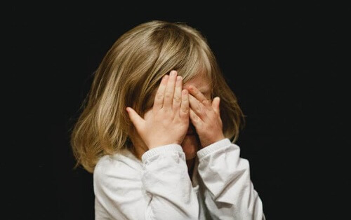 bimba si copre il volto con mani