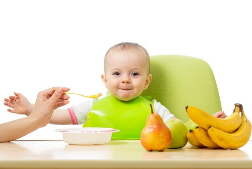 bimbo mangia pappina seduto con accanto banane