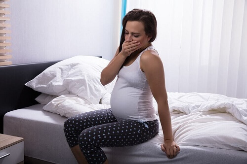 donna appena alzata incinta sbadiglia su letto