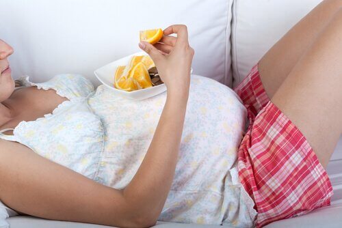 donna incinta su divano mangia arance