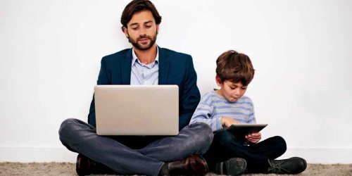 padre e figlio seduti vicini giocano con il computer