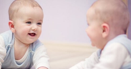 un neonato sorride davanti allo specchio