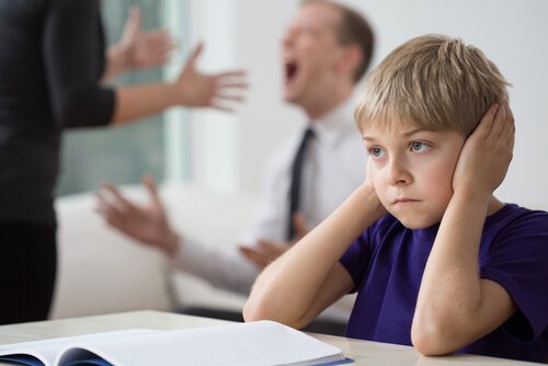Bambino con mani sulle orecchie per non sentire i genitori che discutono
