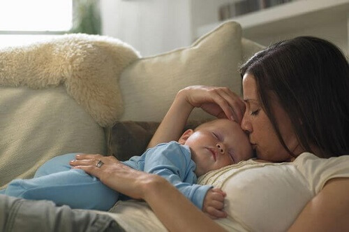 Mamma con bimbo in braccio sul divano