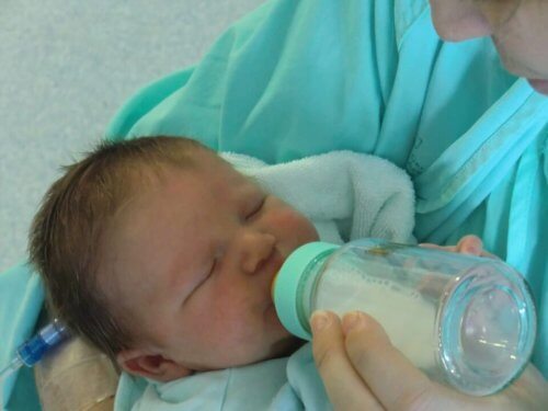 Neonato prende il latte con il biberon