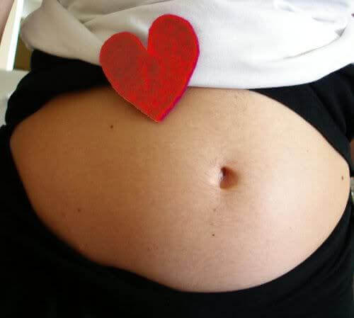 Donna incinta con un cuore sulla pancia