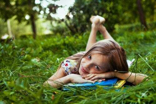 Bambina legge sull'erba e stimola l'apprendimento durante le vacanze